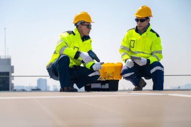 Fabrika çatısındaki güneş panellerini denetleyen teknisyen. Güvenlik donanımı takan bir mühendis, fabrikanın çatısına kurulmuş güneş panelleri üzerinde bakım yapıyor ve en uygun enerji verimliliğini sağlıyor..
