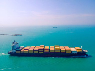 Yüklenen ve boşaltılan bir kargo gemisinin havadan bakış açısı hareketli bir limanda ve anakaradan denize açılışı