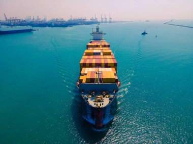 Yüklenen ve boşaltılan bir kargo gemisinin havadan bakış açısı hareketli bir limanda ve anakaradan denize açılışı