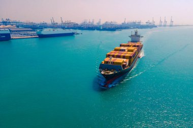 Yüklenen ve boşaltılan bir kargo gemisinin havadan bakış açısı hareketli bir limanda ve anakaradan denize açılışı