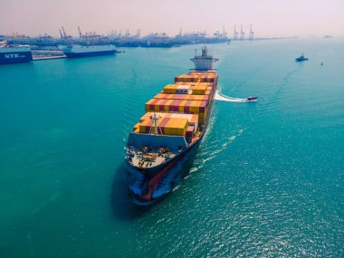 Yüklenen ve boşaltılan bir kargo gemisinin havadan bakış açısı hareketli bir limanda ve anakaradan denize açılışı