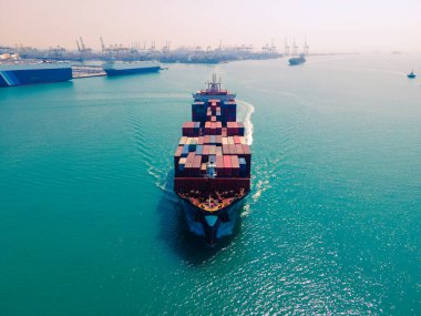 Yüklenen ve boşaltılan bir kargo gemisinin havadan bakış açısı hareketli bir limanda ve anakaradan denize açılışı