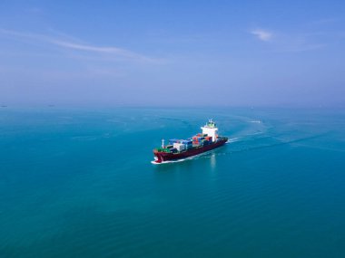 Yüklenen ve boşaltılan bir kargo gemisinin havadan bakış açısı hareketli bir limanda ve anakaradan denize açılışı