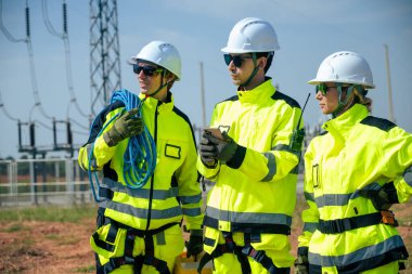 Güvenlik teçhizatı kullanan bir mühendis yenilenebilir enerji alanındaki rüzgar türbininin tabanını yakından inceler..