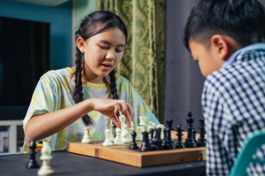 Akıllı çocuklar masa oyunundan zevk alıyorlar. Bir sonraki hamlelerini dostça bir satranç maçında yapıyorlar..