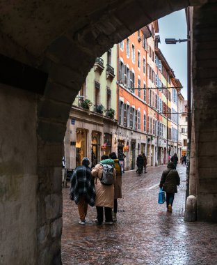 Annecy, France - January 7, 2022: People walking in rainy winter weather in medieval historical old town of french Annecy with colorful facades