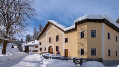 Cinuos-Chel, Switzerland - February 3, 2022: Snow covered village of Cinuos Chel and typical traditional historical houses in Engadine, Graubunden, Switzerland