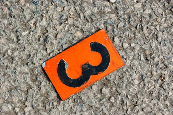 Numero Una Placca Metallo Arancione Stesa Sul Pavimento — Foto Stock
