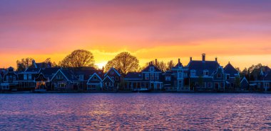 Hollanda 'daki ikonik Zaanse Schans binalarının muhteşem bir akşam manzarası, güzel bir günbatımı ufkuna ev sahipliği yapıyor..