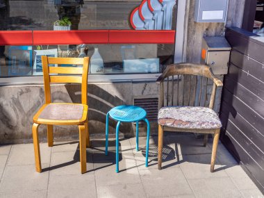 Farklı malzemelerden kullanılmış ve kısmen kırılmış bir grup sandalye..