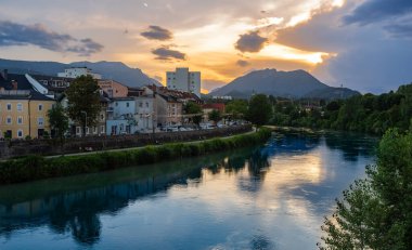 Villach, Avusturya - 12 Temmuz 2023: Günbatımında Drau nehri boyunca Avusturya 'nın Villach kentinin manzarası