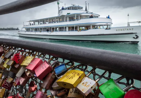 stock image Constance, Germany - August 29, 2023: Locks on the fence at Lake Constance and a tourist boat with the sign Konstanz