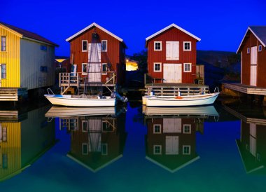 Idyllic isviçre ahşap evler ve tekneler mavi saatte Smogen balıkçı köyündeki deniz kanalı boyunca.