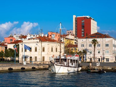 Koper, Slovenya - 11 Kasım 2023: Koper kentinin modern ve eski binalarının önünde küçük bir tekne denize demirledi