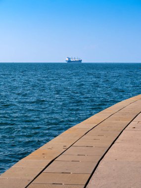 Koper, Slovenya - 11 Kasım 2023: Minimalist fotoğraf - Trieste körfezindeki uzak bir kargo gemisinin iskelesinden görüntü