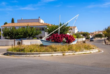 Saintes Maries de la Mer, Fransa - 3 Ekim 2023 Saintes Maries de la Mer 'deki kavşağı süslemek için kırmızı çiçeklerle dolu bir yelkenli.