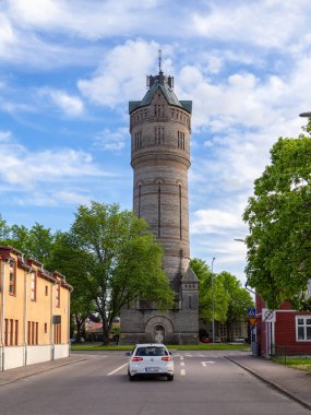 Lidkoping, İsveç - 27 Mayıs 2023: Eski su kulesinin manzaralı bulutlu akşamında Lidkoping Caddesi