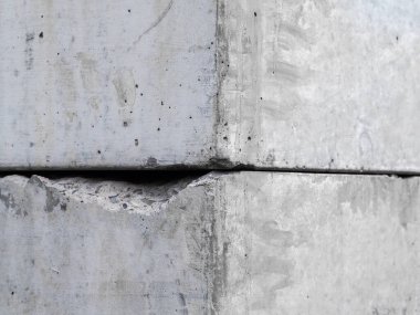 Endüstriyel ve engebeli hisleri gösteren pürüzlü dokuları ve kusurları olan iki beton bloğa yakın çekim.