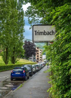 Trimbach, İsviçre - 25 Mayıs 2024: Trimbach 'ta park etmiş arabaların olduğu sokak manzarası, yemyeşil binalar, ağaçlar, bulutlu gökyüzü.