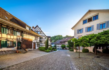 İsviçre 'nin ortaçağ Regensberg köyü. Geleneksel mimari, kilise, taş kule, kaldırım taşı sokaklar ve açık mavi gökyüzü altında yeşillik..