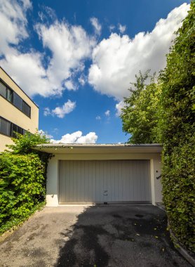 Kapalı kapılı, yeşil ve modern binalarla çevrili, parlak mavi gökyüzünün altında..