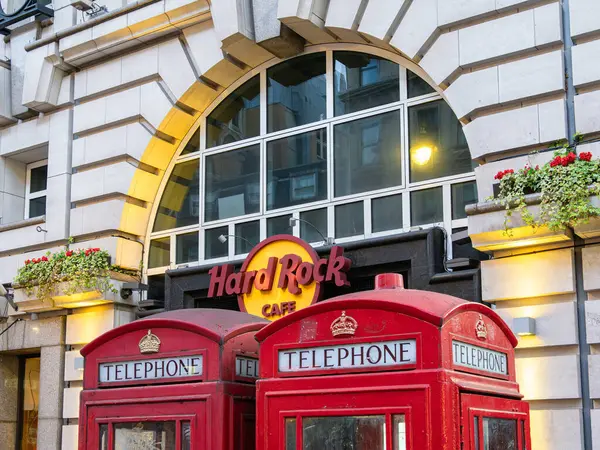 stock image London, United Kingdom - June 25, 2024: Iconic Hard Rock Cafe entrance in London with red telephone booths and floral touches.