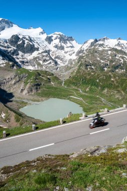 Serene motorcycle drive through majestic mountains. Steingletcher glacier and Steinsee lake at Sustenpass mountain pass. clipart