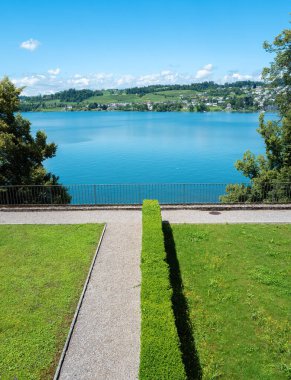 Rapperswil 'de yemyeşil ve mavi gökyüzüyle sakin bir göl manzarası. Negatif boşluk.