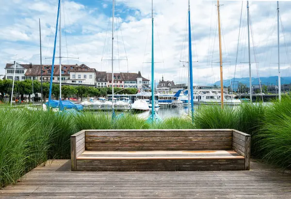 stock image Rapperswil, Switzerland - July 1, 2024: Serene bench by Zurich lake in the marina of Rapperswil with lush greenery, peaceful ambiance.