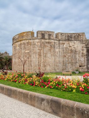 Saint Malo, Fransa - 20 Temmuz 2024: Brittany, Saint Malo 'nun tarihi şehir duvarı, canlı dekoratif çiçek yatağı, bulutlu gökyüzü.