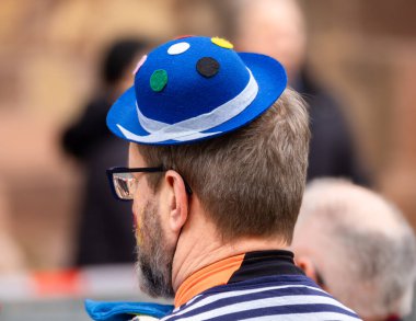 Freiburg im Breisgau, Almanya - 12 Şubat 2024: Maskeli Balo. Mavi madalyalı karnaval şapkalı bir adam