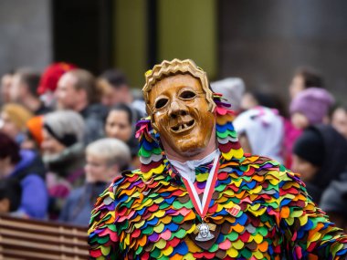 Freiburg im Breisgau, Germany - February 12, 2024: Masquerade. Beautiful mask in a carnival parade with blurred people in background. clipart