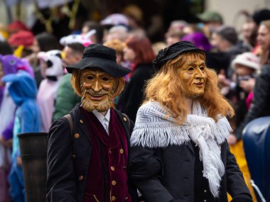 Freiburg im Breisgau, Germany - February 12, 2024: Masquerade. Beautiful masks in a carnival parade with blurred people in background. clipart