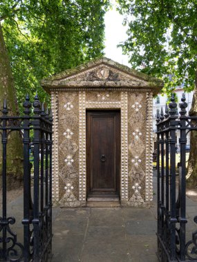 London, United Kingdom - June 25, 2024: Shell hut in a Grosvenor gardens of London, surrounded by black wrought iron gates and trees. clipart