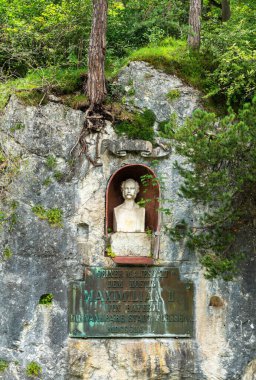 Fussen, Almanya - 5 Ağustos 2024: Kayalık bir uçurumda oyulmuş bir oyuk ile çevrili Maximilian II büstünün yer aldığı taş bir anıt. Baskının altında yazılı bir plaket var..