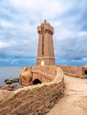 Pembe granit taşların kayalık oluşumlarını içeren manzaralı bir kıyı manzarası. Ploumanach, Brittany, Pembe granit sahili feneri