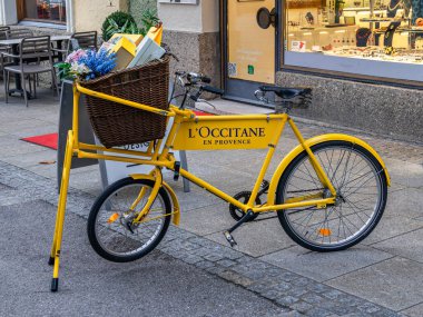 Salzburg, Avusturya - 24 Ekim 2024: Olivier Baussan tarafından kurulan Fransız güzelliği ve cilt bakımı markası Occitane en Provence 'nin sarı reklam bisikleti.