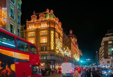 Londra, Birleşik Krallık - 25 Kasım 2024: Harrods simgesel mağazası karanlıkta, Noel aydınlatması ve süslemeleri.