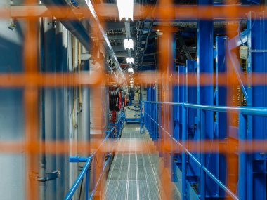 Cenevre, İsviçre - 5 Şubat 2025: Güvenlik bariyeri, ızgarası, boruları ve sarılı kabloları olan sanayi koridoru.