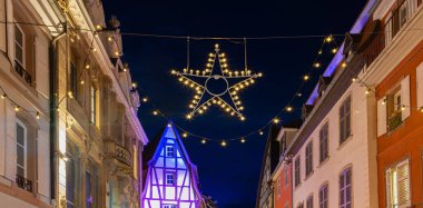 Colmar, Fransa - 28 Kasım 2024: Colmar 'ın büyüleyici caddesi, şenlikli Noel ışıkları ve tarihi mimari ile süslenmiş.