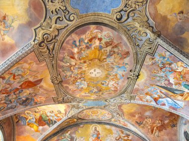 Michaelbeuern, Avusturya - 22 Ekim 2024: Kilisenin tavanında melekler ve azizlerin canlı renkler ve dekoratif mimari unsurlarla yer aldığı dini sahneleri gösteren ayrıntılı bir fresk.