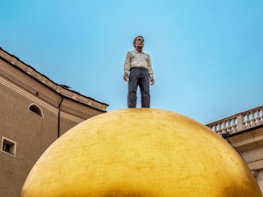 Salzburg, Avusturya - 24 Ekim 2024: Kapitelplatz, Salzburg 'da bulunan Sphaera heykeli - altın bir kürenin üzerinde rahatlatıcı bir duruş içinde duran bir adam figürü.