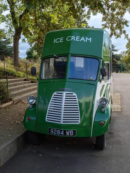Londra, Birleşik Krallık - 27 Ekim 2024: Ağaçlarla çevrili, caddeye park edilmiş yeşil bir Morris dondurma kamyonu.