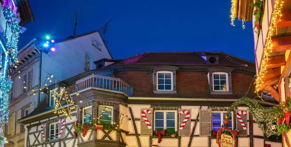 Colmar, Fransa - 28 Kasım 2024: Colmar 'ın Noel ışıkları ve dekorasyonlarıyla süslenmiş büyüleyici bir sokak sahnesi. Geleneksel yarı keresteli evler aydınlatılır.