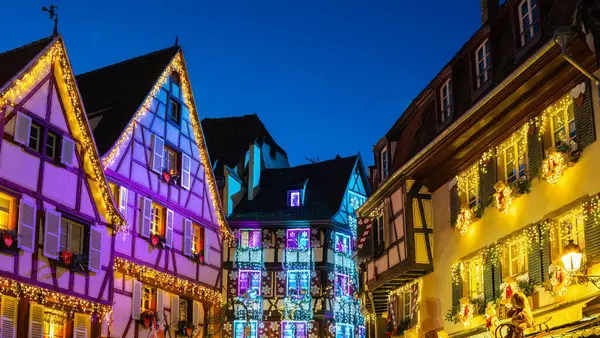 Colmar, Fransa - 28 Kasım 2024: Colmar, Alsace 'de alacakaranlıkta Noel ışıklarıyla süslenmiş renkli yarı keresteli evler.