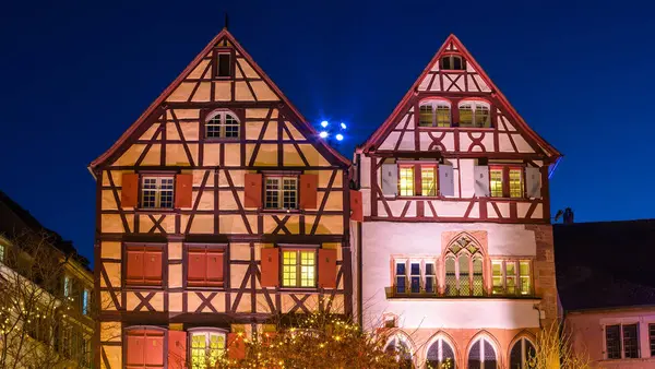  Colmar 'da iki geleneksel yarı keresteli ev. Noel zamanı geceleri pencereleri aydınlatılmış. Klasik Alsas mimarisi sergileniyor..