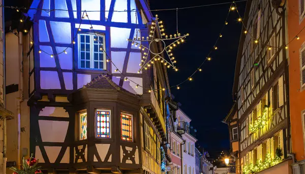 Colmar, Fransa - 28 Kasım 2024: Colmar 'ın büyüleyici caddesi, şenlikli Noel ışıkları ve tarihi mimari ile süslenmiş.