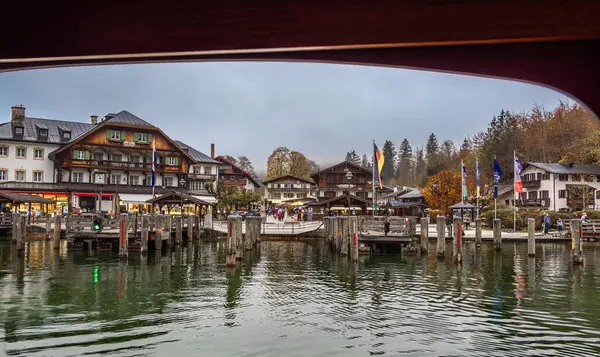 Schonau, Almanya - 23 Ekim 2024: Schonau am Konigssee göl köyü manzaralı geleneksel ahşap binalar ve sonbahar ağaçlarıyla çevrili rıhtım.