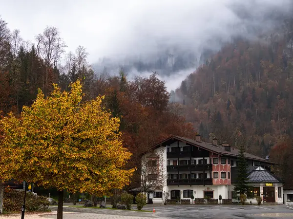 Schonau, Almanya - 23 Ekim 2024: Sonbahar yeşillikleri ve sisli dağlarla çevrili tuhaf bir alp oteli Konigssee Hof.