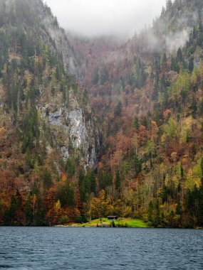 Konigssee Gölü sisli dağlar ve yoğun sonbahar yapraklarıyla çevrilidir..